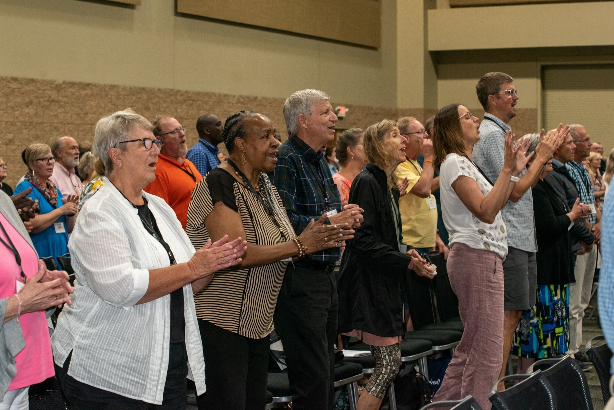 Group of people of various ages and races worshipping together in a room