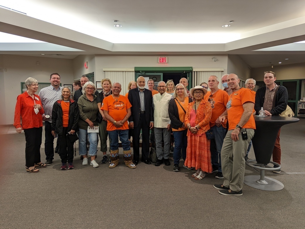 group of people gathered for a photo mostly wearing orange shirts