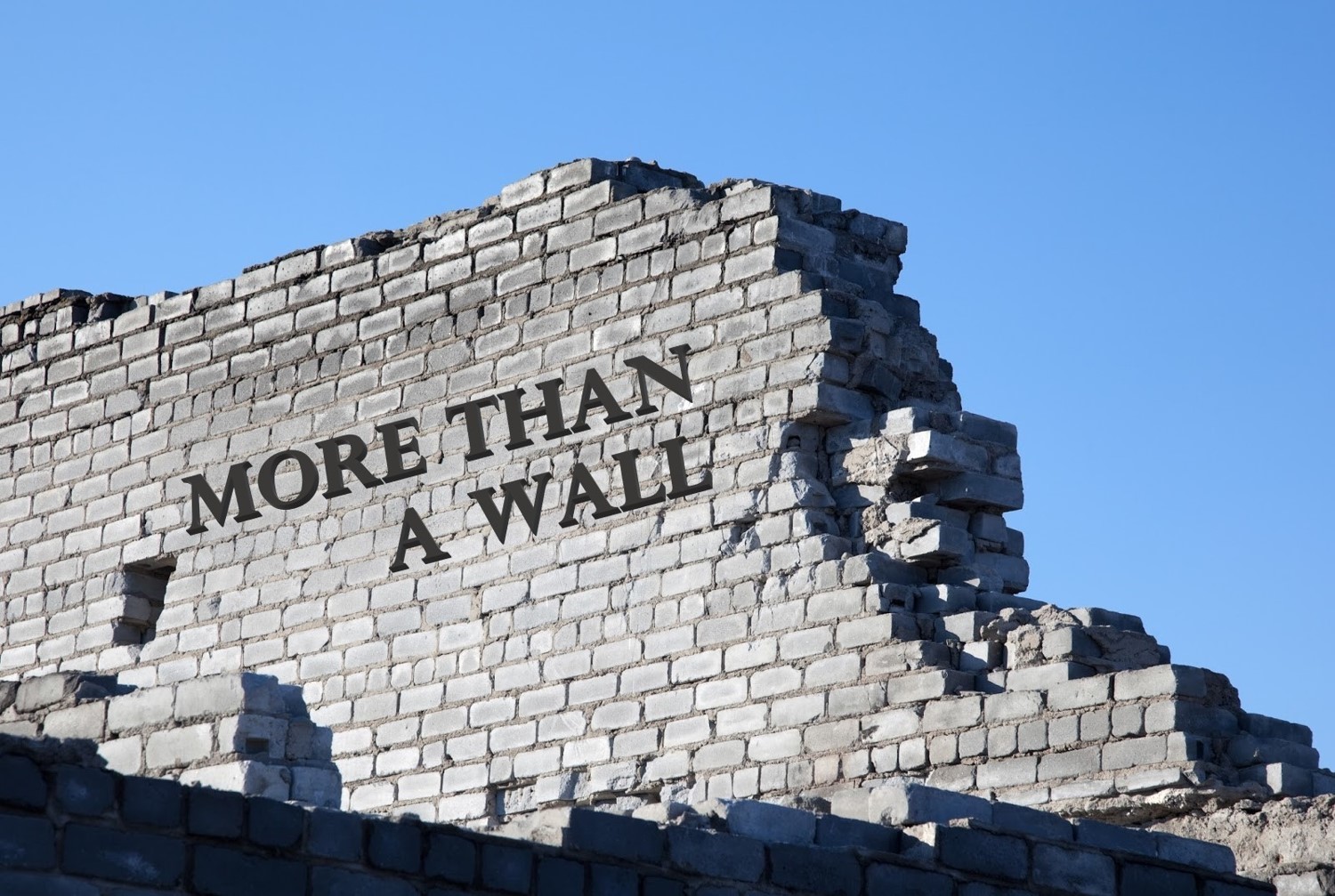 the text "more than a wall" on a half built wall